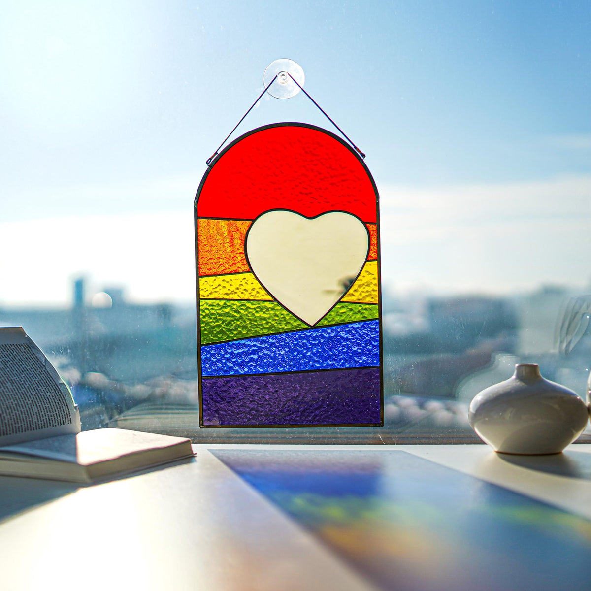 Stained glass rainbow pride heart suncatcher in sunlight, vivid red orange yellow green blue purple stripes, mirror heart, handmade Ukraine
