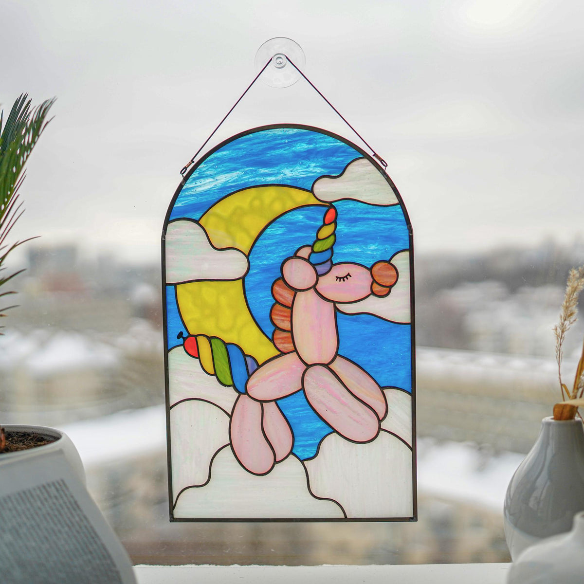 Stained glass balloon unicorn panel in a bright window with city view, kids room nursery decor