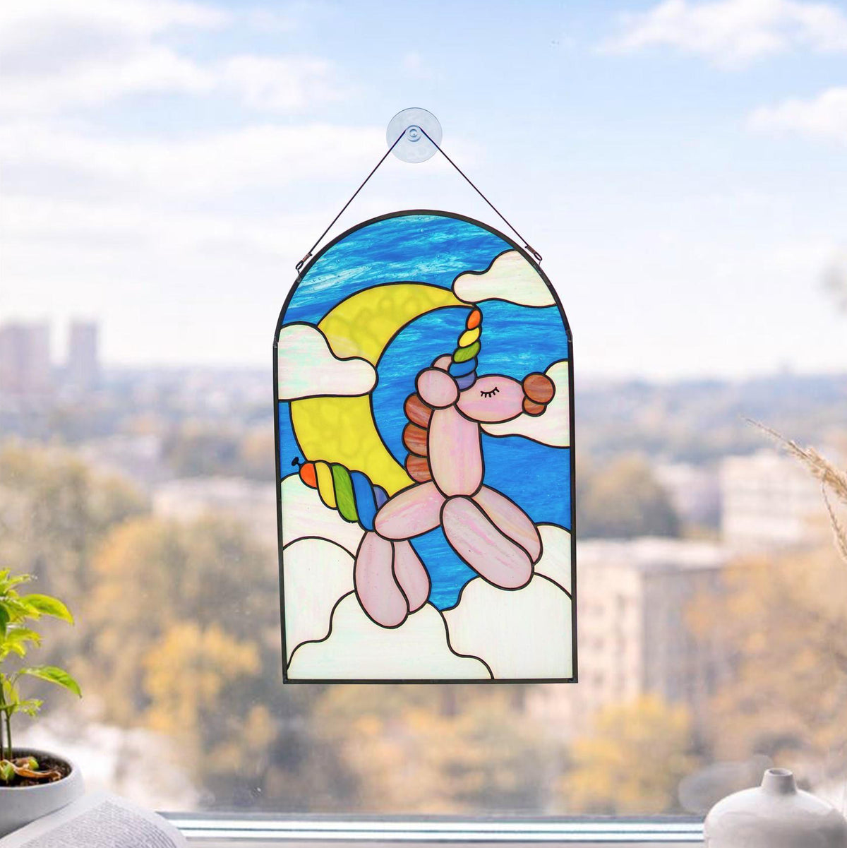 Handmade stained glass balloon unicorn panel hanging in a sunny window, Tiffany copper foil technique