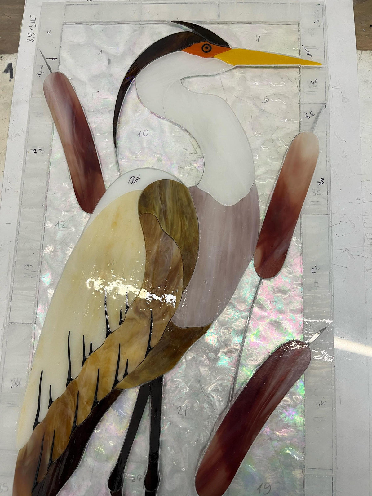Close-up detail of handmade stained glass heron panel, copper foil technique, textured cathedral glass