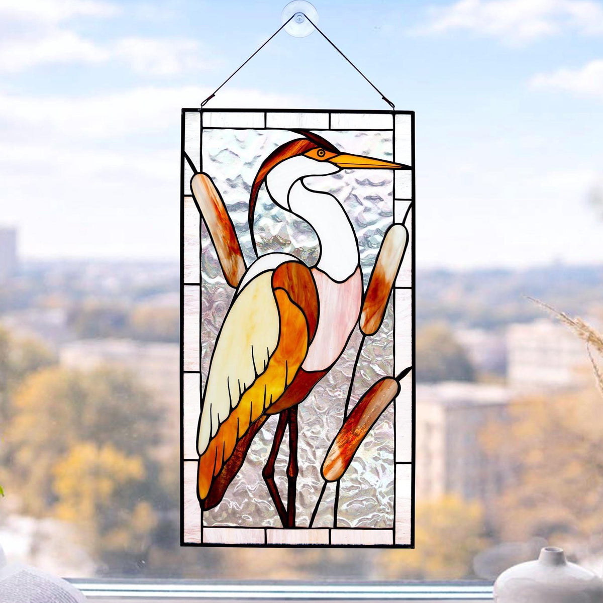 Handmade stained glass heron panel with reeds, hanging in a sunny window, Tiffany copper foil technique