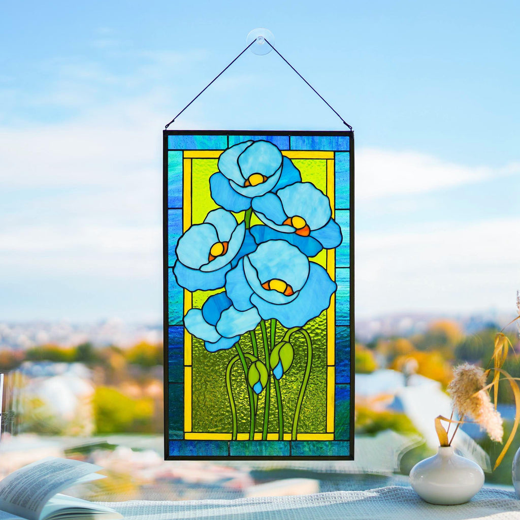 Himalayan blue poppy stained glass panel hanging in a sunny window, turquoise petals and vivid green background