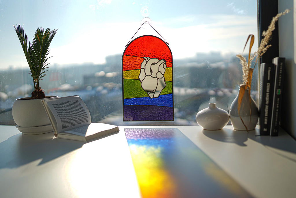 Close-up of mirror heart rainbow suncatcher showing glass texture and prism light reflections, pride home decor