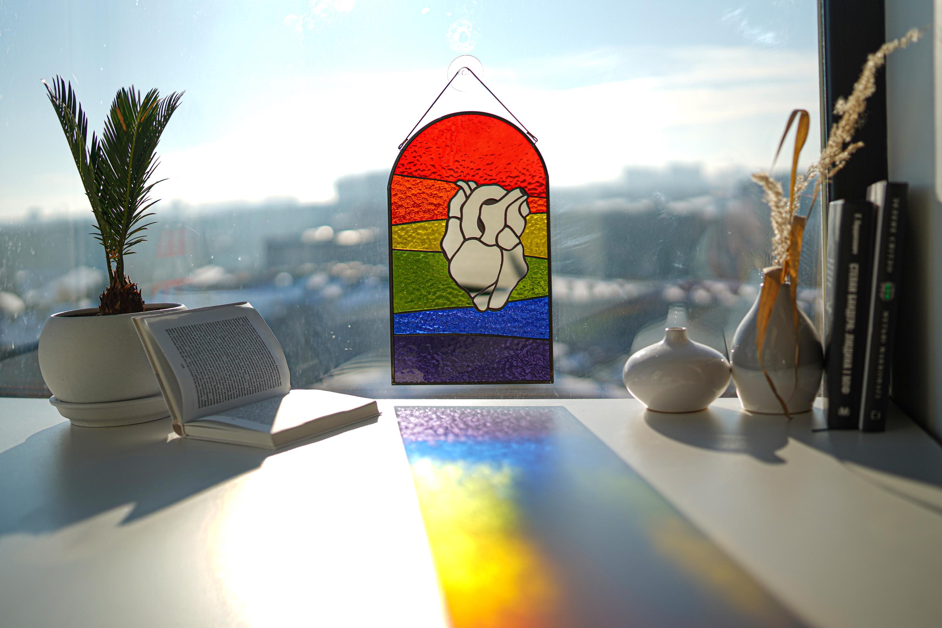 Close-up of mirror heart rainbow suncatcher showing glass texture and prism light reflections, pride home decor