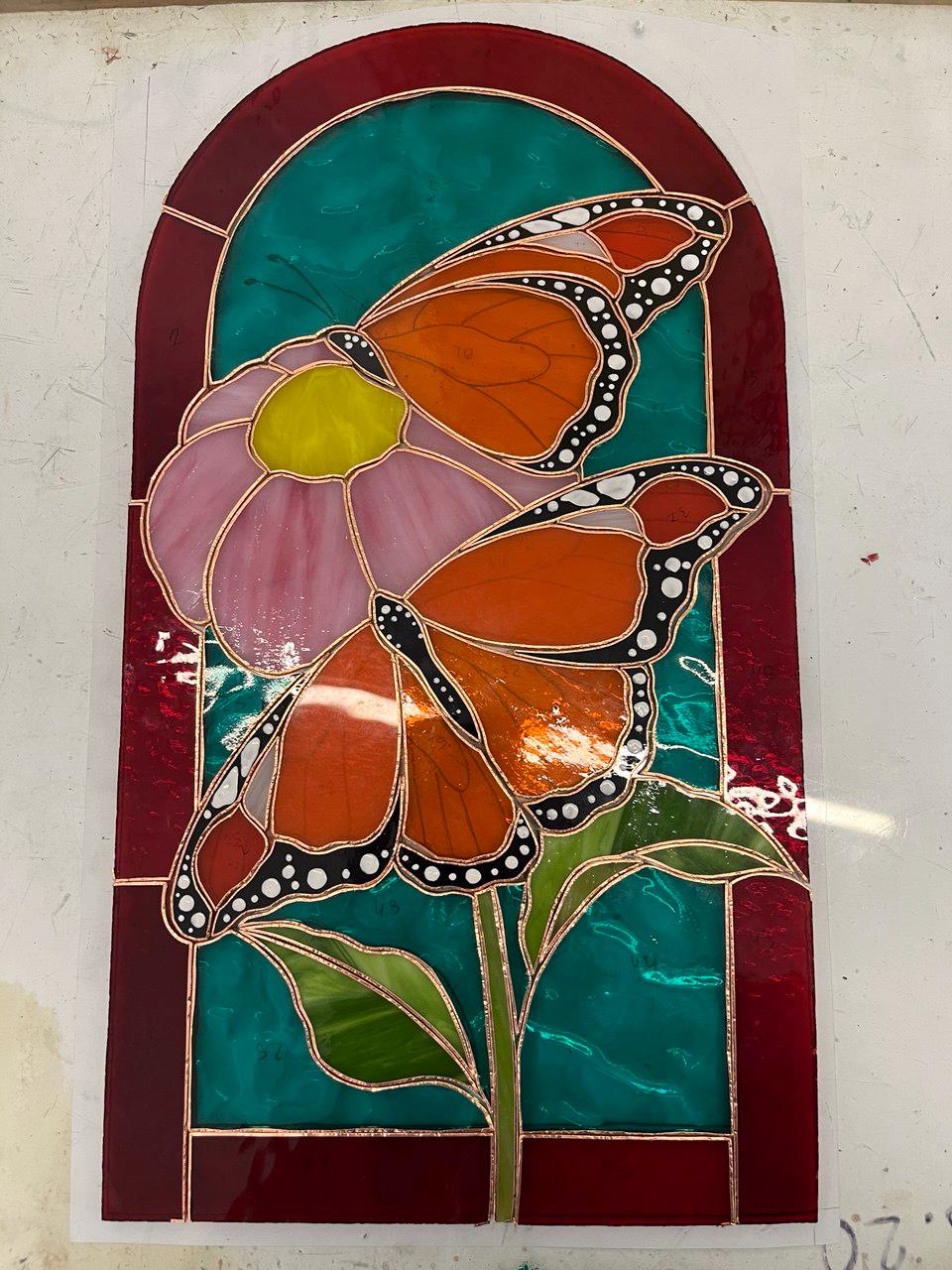 Handmade stained glass monarch butterfly panel during assembly, copper foil and cathedral glass pieces