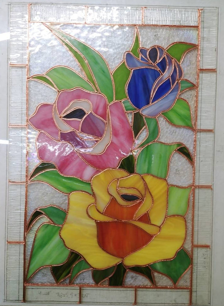 Handmade stained glass roses panel during assembly, copper foil and cathedral glass pieces laid out