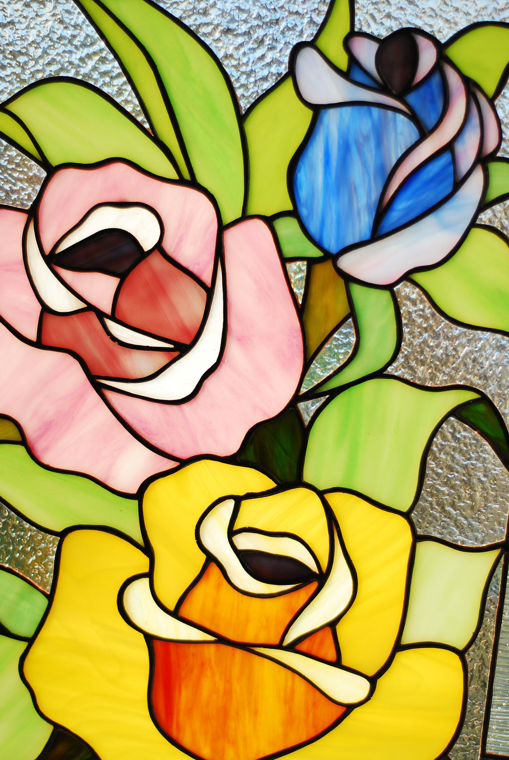 Close-up of handmade stained glass multicolored roses, vibrant pink yellow and blue cathedral glass petals