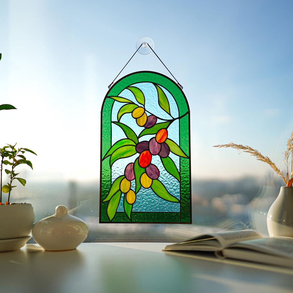 Stained glass olive branch arched panel in a sunny window with indoor plant, Mediterranean botanical decor