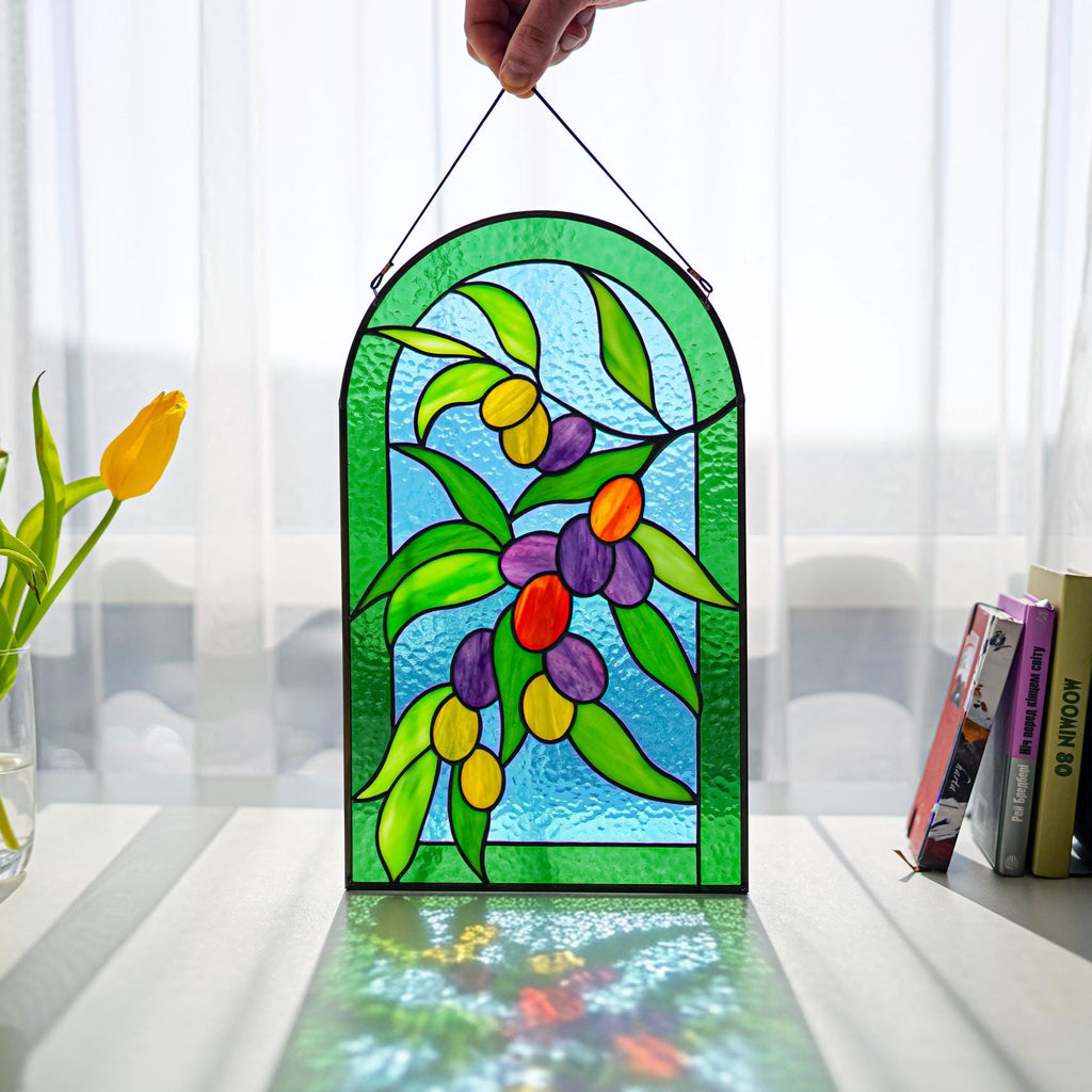 Handmade stained glass olive branch panel with colorful olives, held up in a sunny window, Tiffany copper foil technique