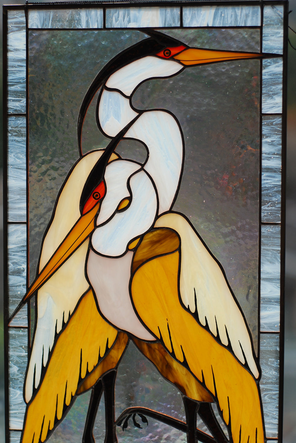 Front view of stained glass pair of herons panel, white and amber cathedral glass, black zinc frame