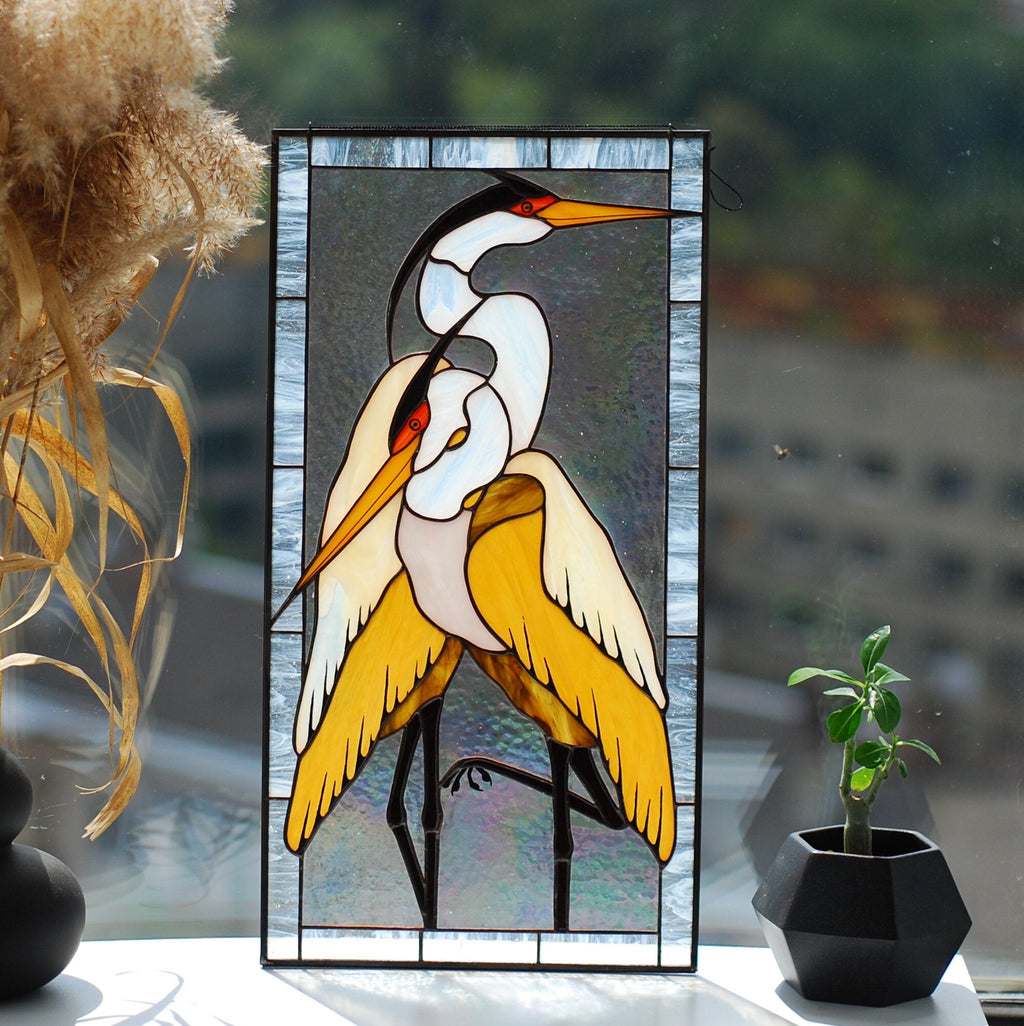 Stained glass heron pair panel in a sunny window with decorative vases, coastal nature-inspired decor