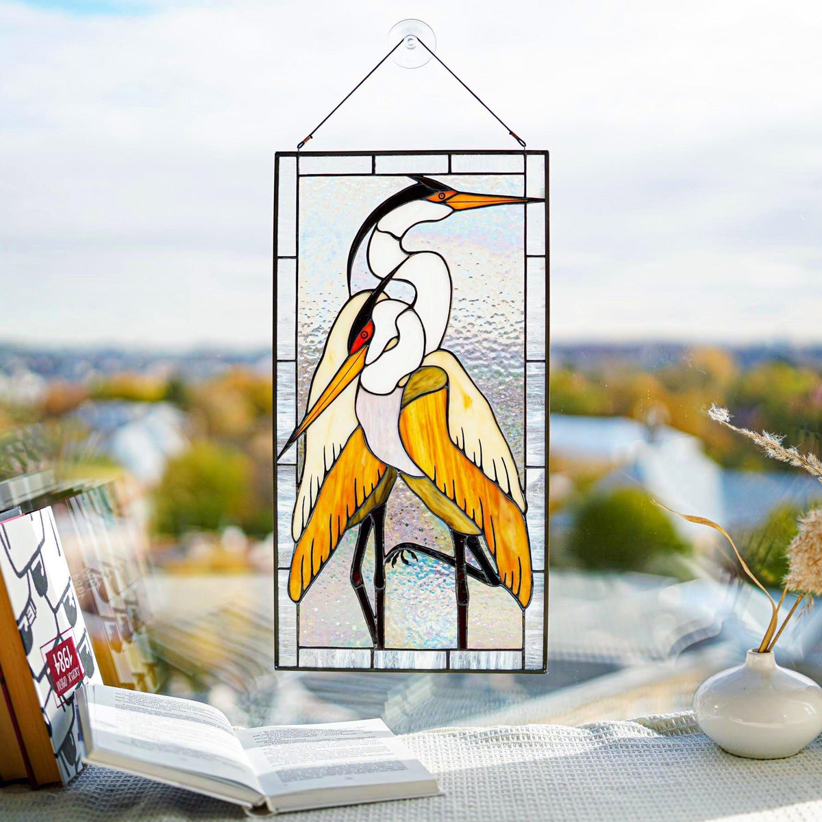 Handmade stained glass pair of herons panel with white and golden heron, hanging in a bright window, Tiffany copper foil technique