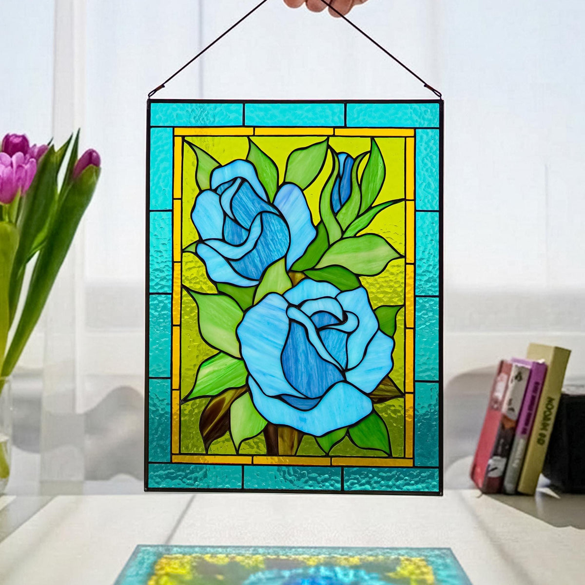 Handmade stained glass blue rose panel held up in a bright window, turquoise and teal roses with green leaves, Tiffany copper foil, 11x14 inches
