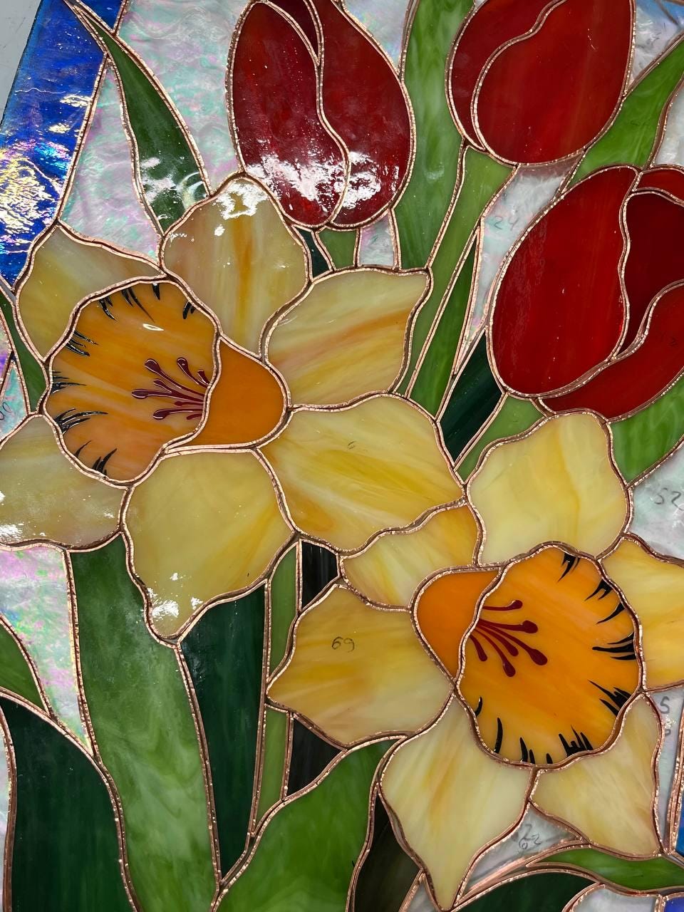 Close-up of handcrafted stained glass daffodils, yellow cathedral glass with copper foil detail, work in progress