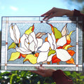 Handmade stained glass magnolia panel held outdoors, white magnolia blossoms with orange and green leaves, Tiffany copper foil, 16x11 inches
