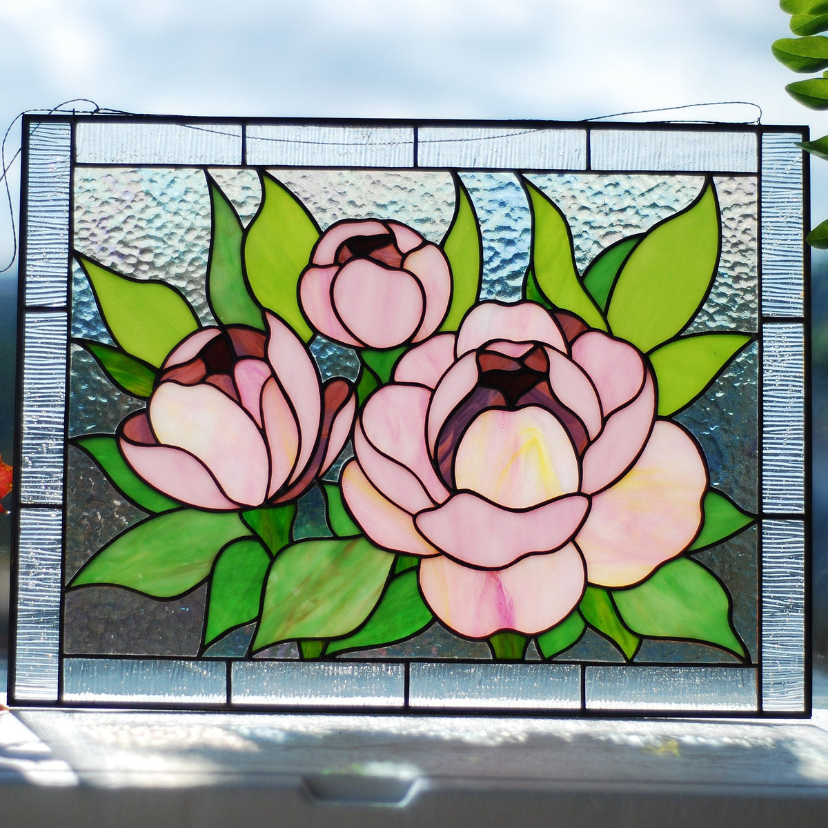 Stained glass pink peony panel on windowsill with red maple leaf and plant, three blooms in soft pink and blush, Tiffany style, 11.5x15.5 in

