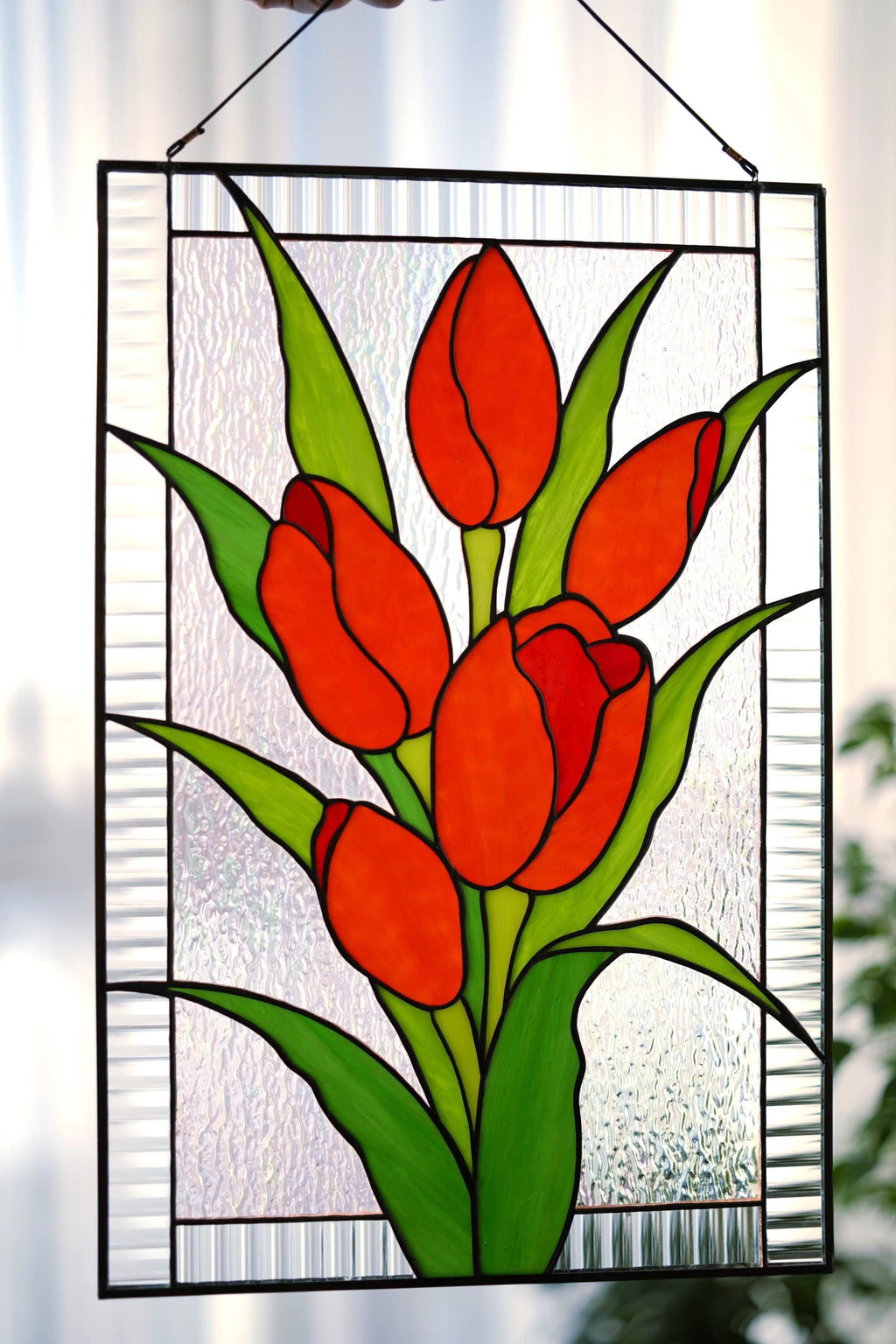 Close-up of stained glass red tulip panel showing vivid red cathedral glass petals and copper foil lines, textured clear background, handmade in Ukraine
