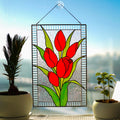 Stained glass red tulip panel on windowsill with plants and books, four bold red blooms on textured clear background, Tiffany style, 16x10.5 in
