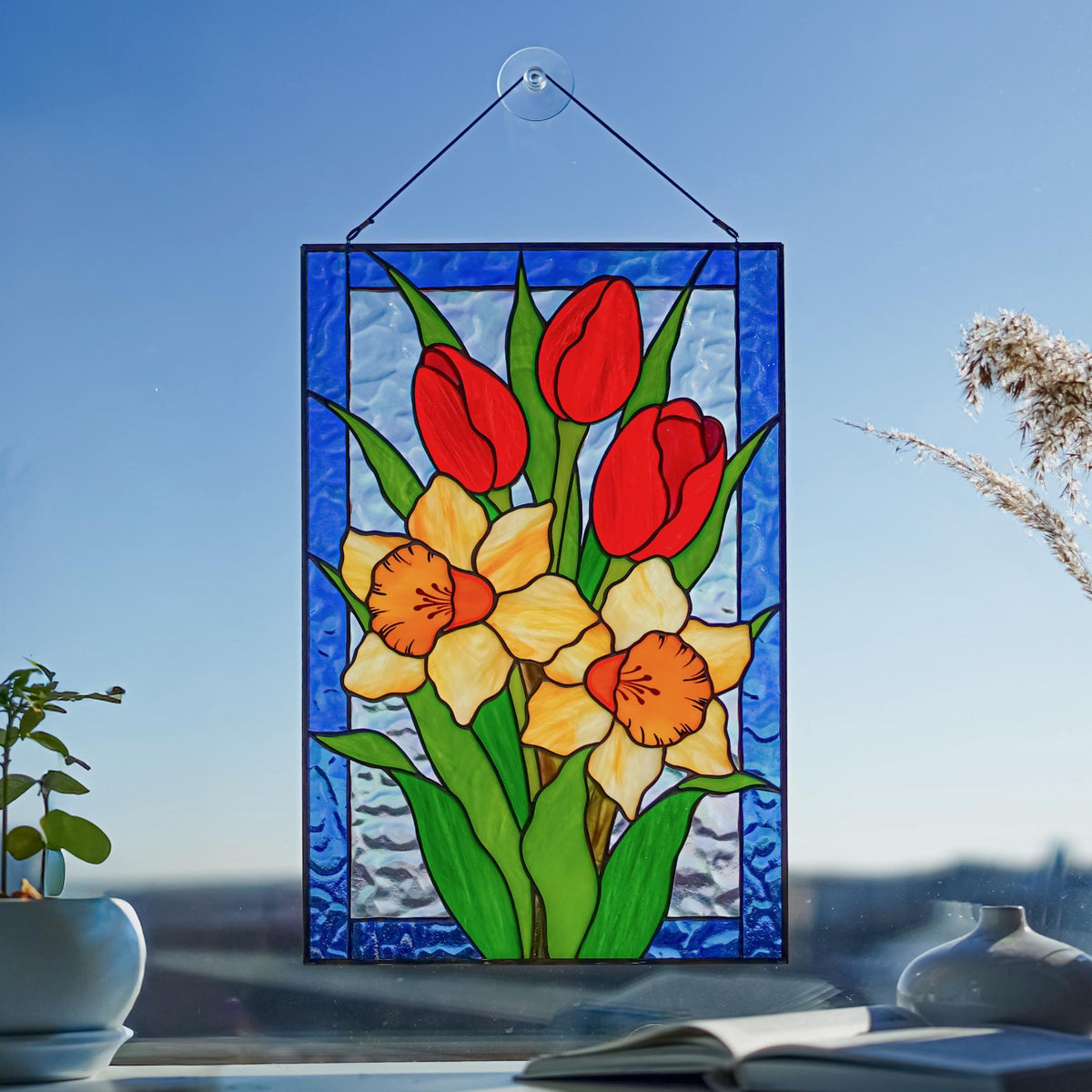 Stained glass tulips and daffodils window hanging with light shining through, spring floral suncatcher
